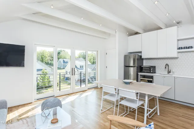 a kitchen with stainless steel appliances a dining table chairs microwave and sink