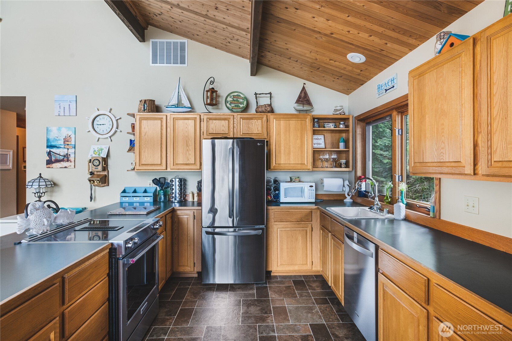 7616 Cypress Way Anacortes, WA 98221 - Photo 21 of 35 a kitchen with stainless steel appliances granite countertop a refrigerator a sink dishwasher a stove with wooden cabinets and floor
