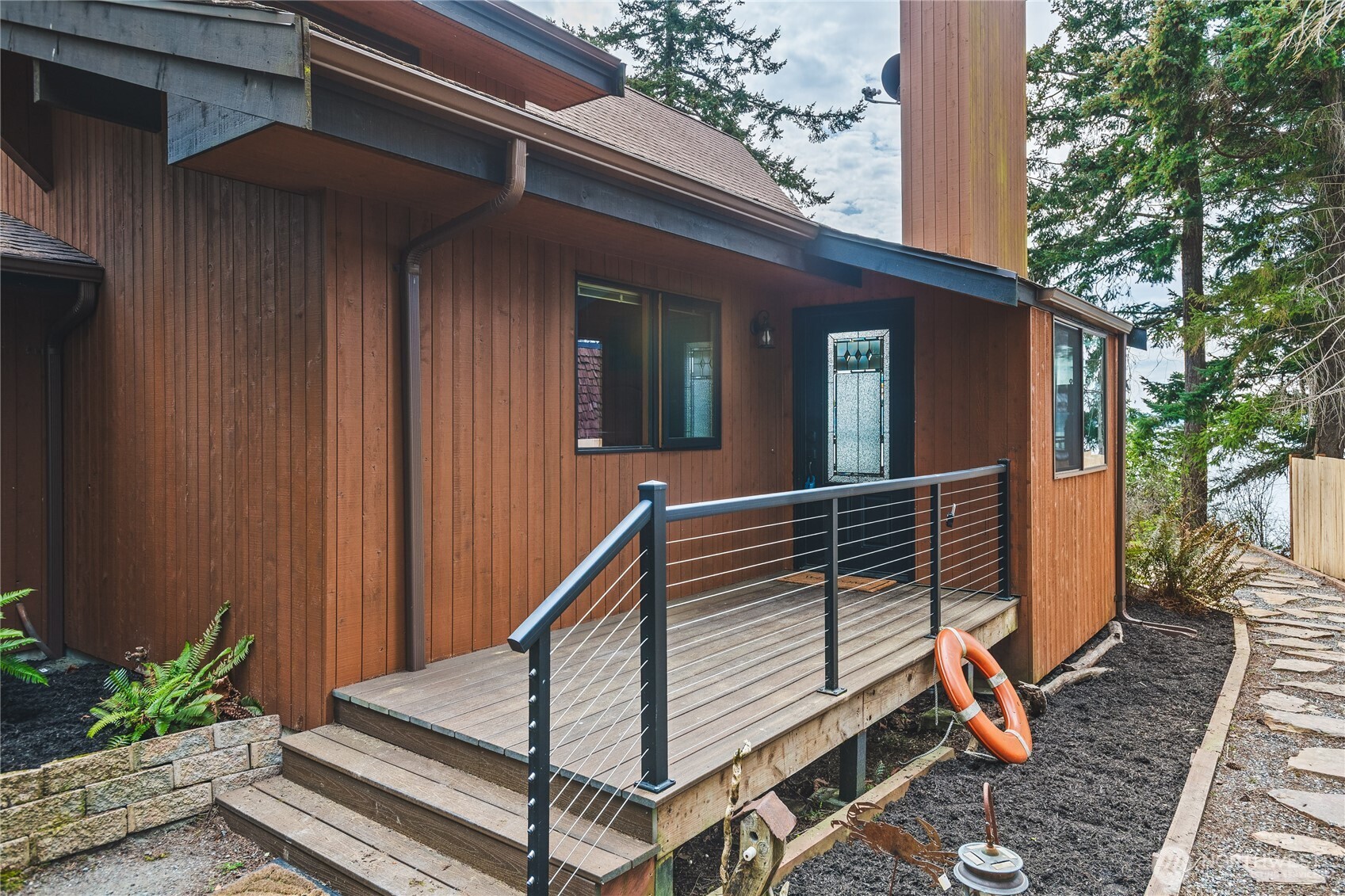 7616 Cypress Way Anacortes, WA 98221 - Photo 9 of 35 a view of wooden house with a large windows and flower plants