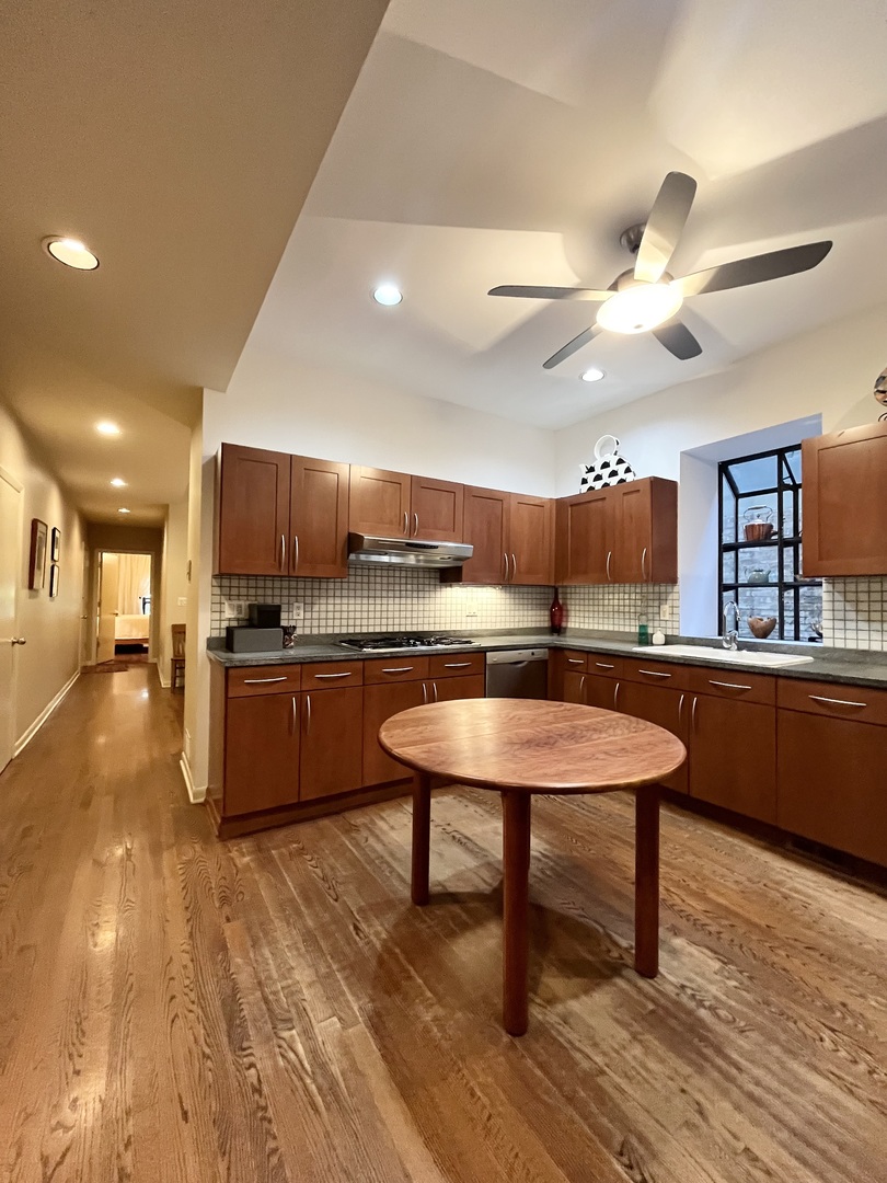 626 West Grace Street, Unit 1E Chicago, IL 60613 - Photo 12 of 29 a kitchen with stainless steel appliances kitchen island granite countertop a table chairs in it and wooden floors
