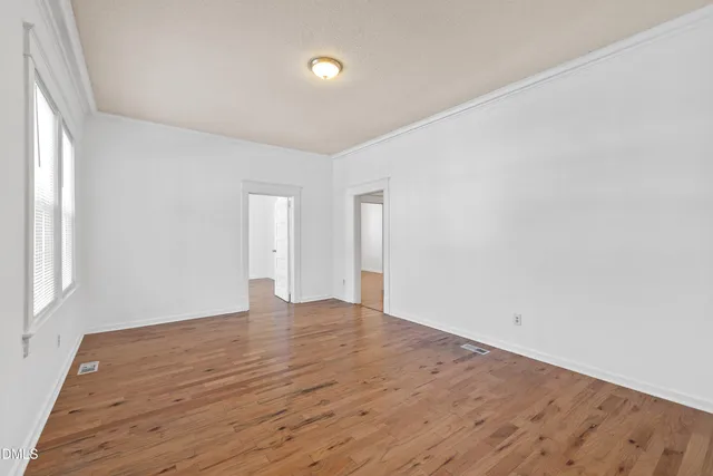 an empty room with wooden floor fan and windows