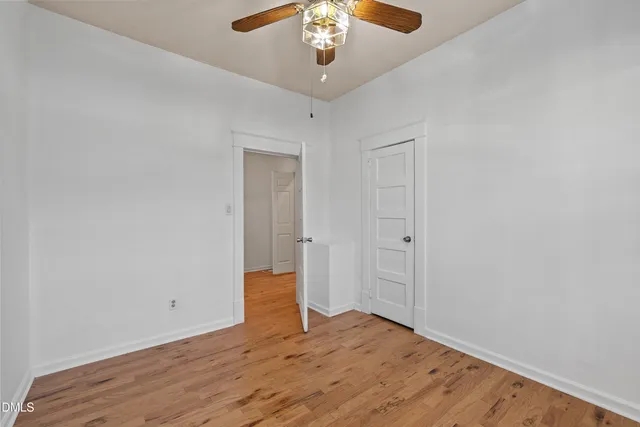 a view of an empty room with wooden floor and windows