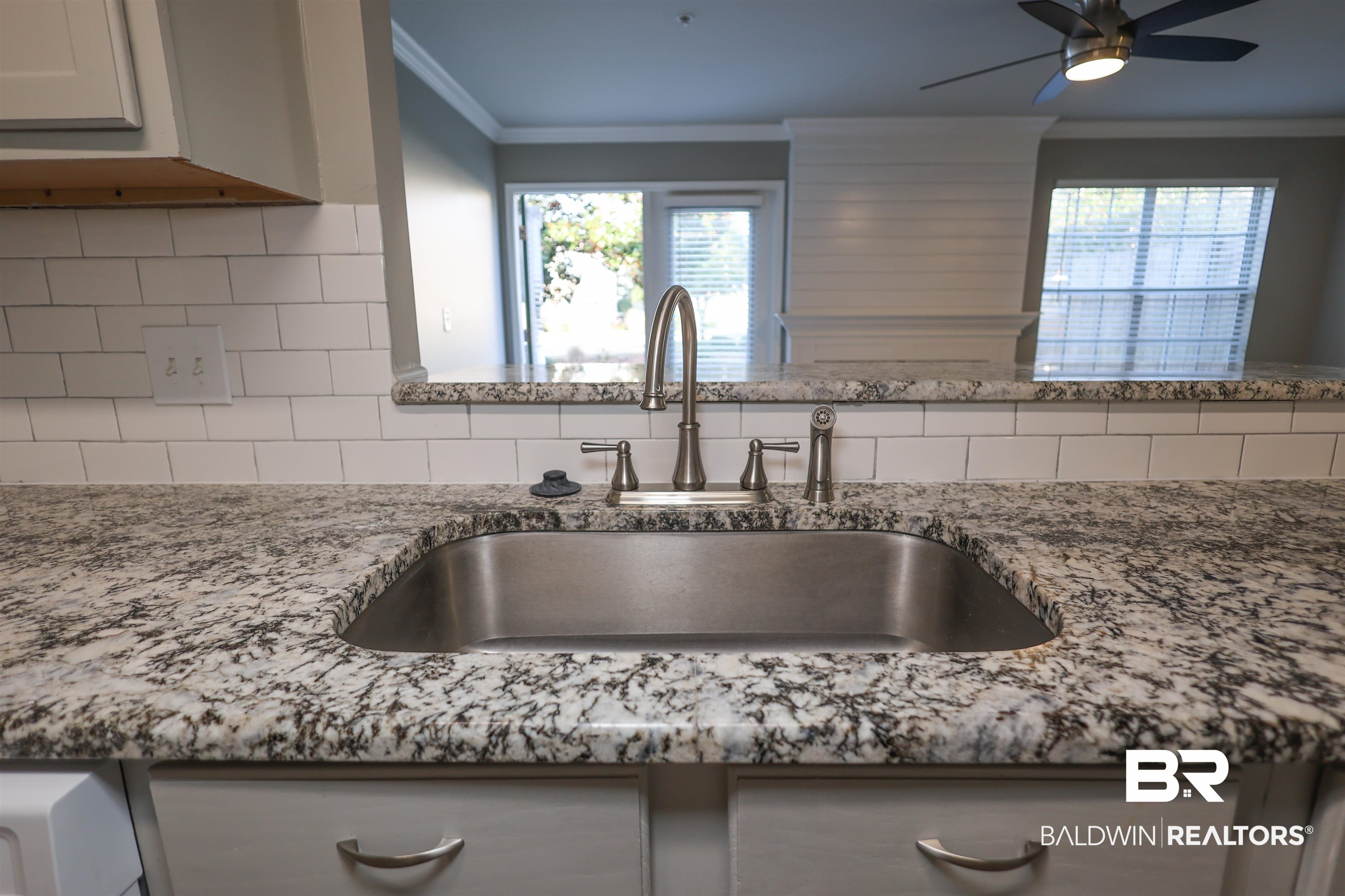 1517 Regency Road, Unit 125 Gulf Shores, AL 36542 - Photo 8 of 26 Kitchen view of light stone countertops, ornamental molding, and ceiling fan