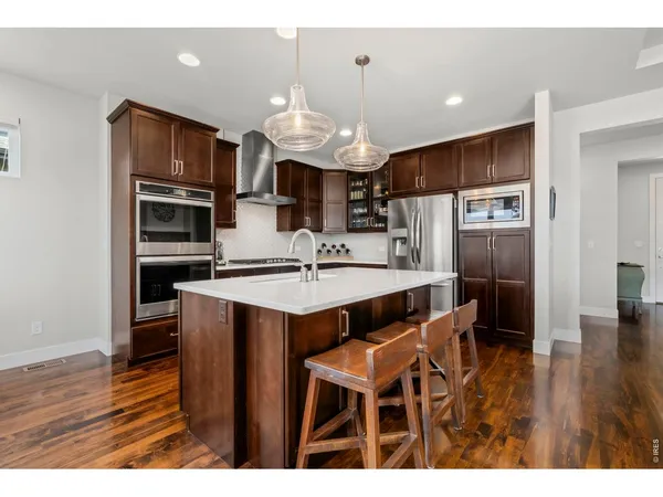 a kitchen with stainless steel appliances granite countertop a sink and wooden floor