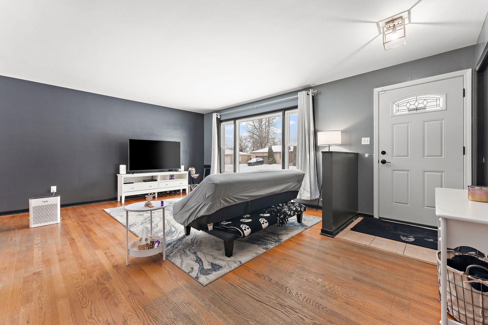 5345 Johnson Street Merrillville, IN 46410 - Photo 2 of 26 a living room with furniture a flat screen tv and a floor to ceiling window