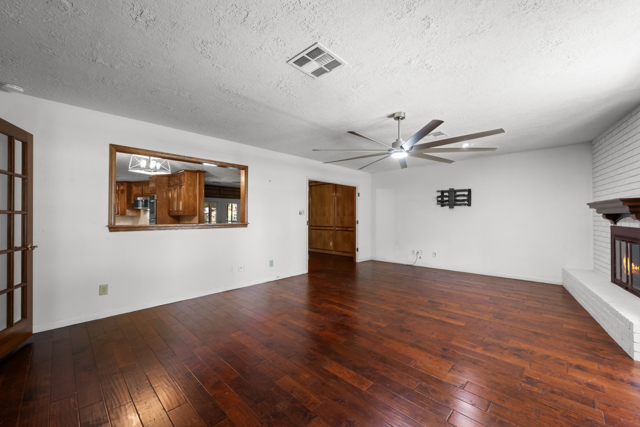 616 Cannan Drive Angleton, TX 77515 - Photo 4 of 49 This spacious family room features rich wood-look flooring, a contemporary ceiling fan, and a cozy fireplace that serves as a natural focal point. The open layout and convenient pass-through to the kitchen create an ideal setting for everyday living and entertaining.