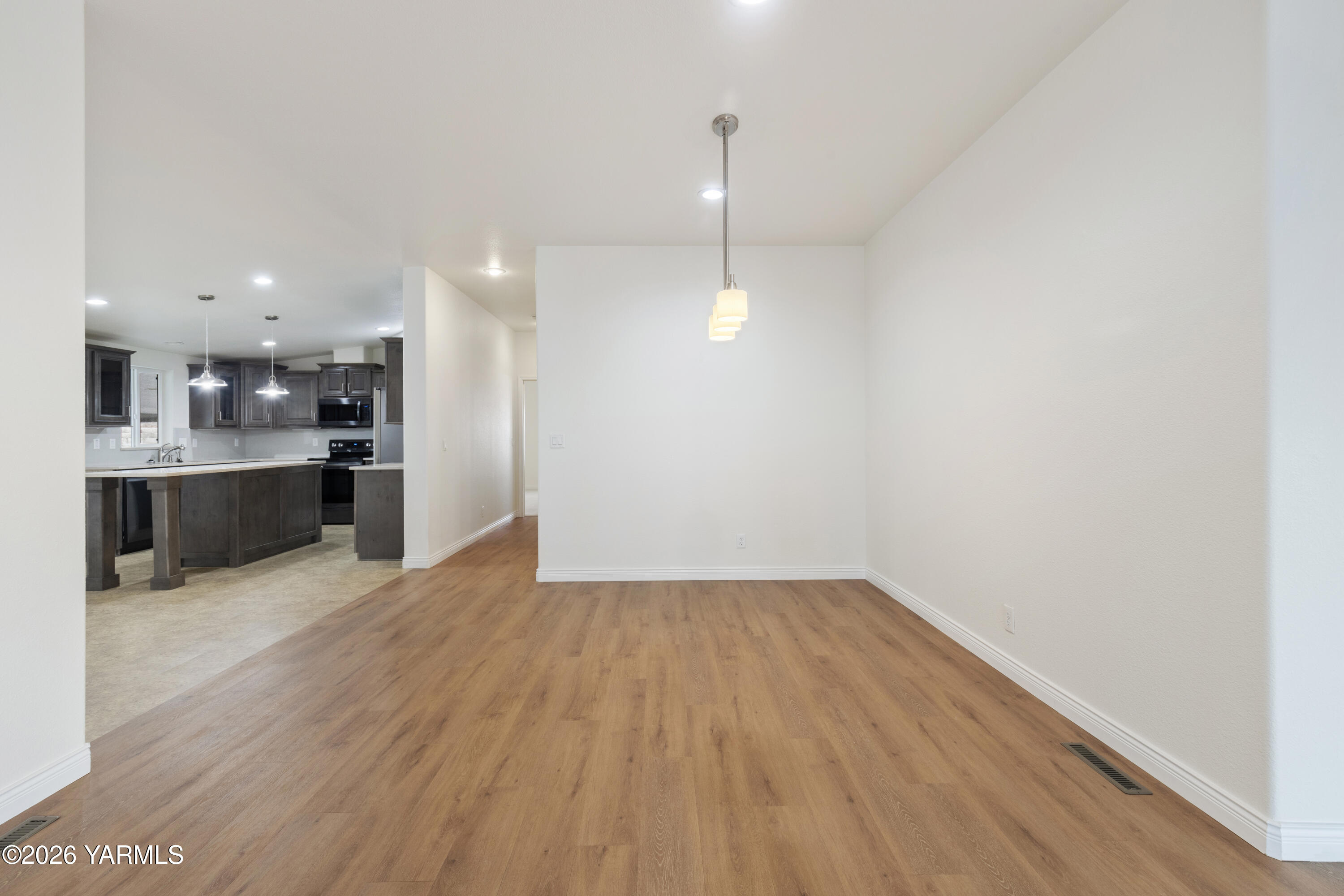 200 Bridle Way, Unit 157 Yakima, WA 98901 - Photo 7 of 30 an empty room with wooden floor and kitchen view