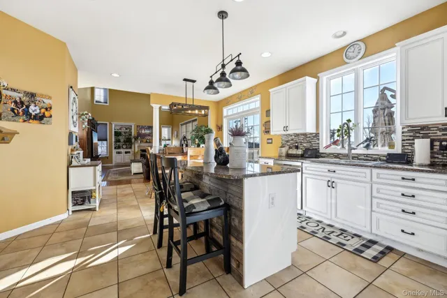 a kitchen with stainless steel appliances kitchen island granite countertop a table chairs and a chandelier