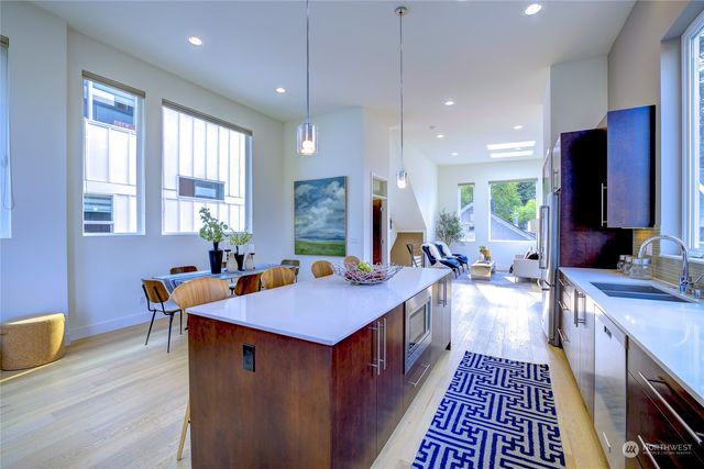 a kitchen with stainless steel appliances granite countertop a stove a sink dishwasher and a refrigerator with wooden floor