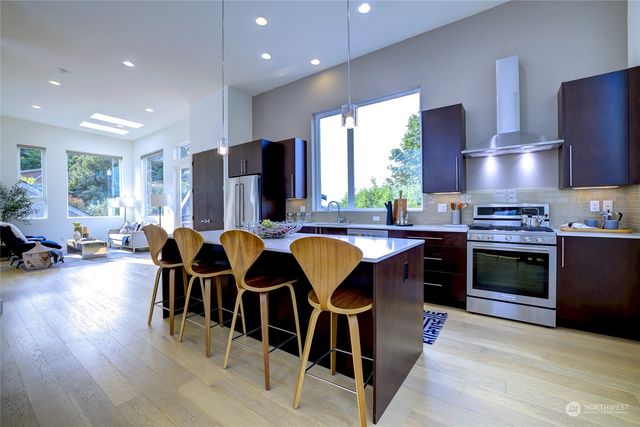 a kitchen with stainless steel appliances granite countertop a stove top oven a sink a dining table and chairs