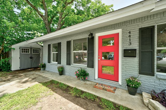 a view of a house with potted plants and a table and chairs