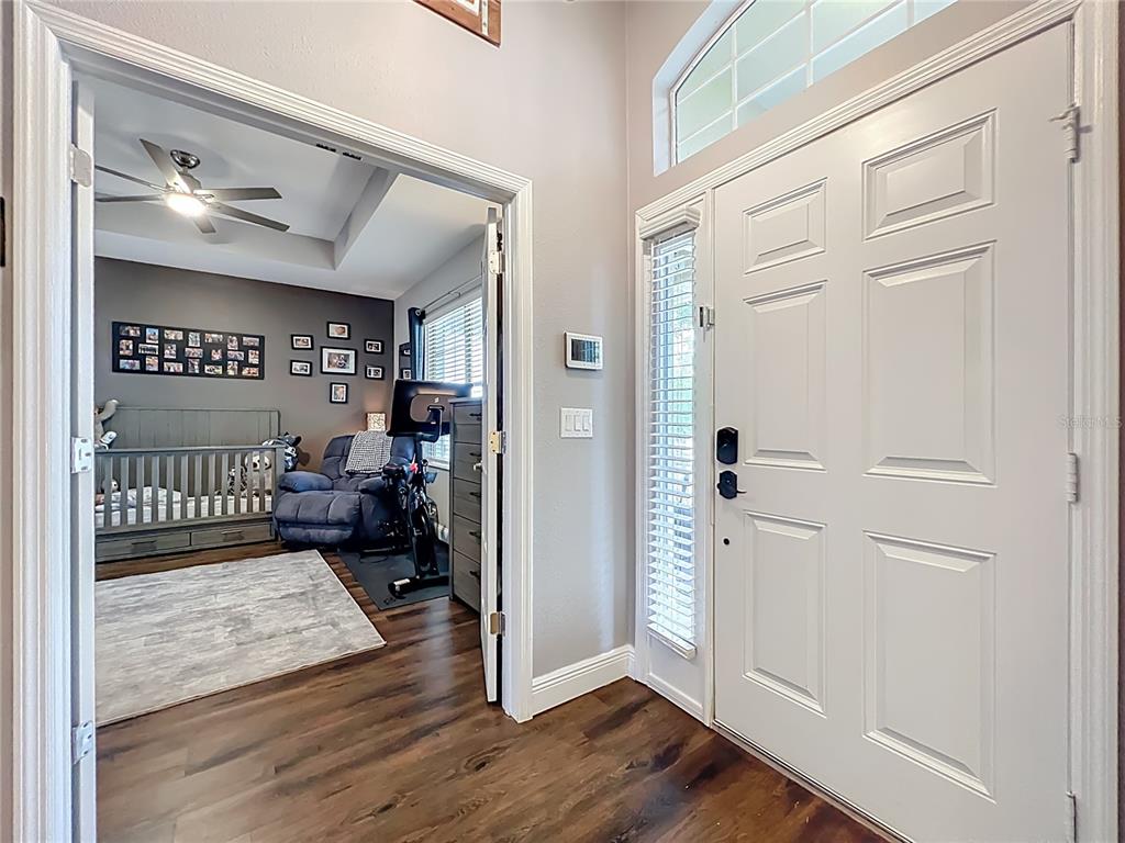 135 Blackstone Creek Road Groveland, FL 34736 - Photo 7 of 62 a view of a hallway to a livingroom with wooden floor and furniture