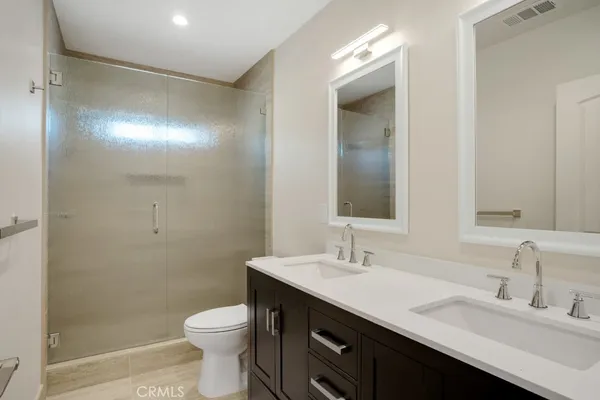 a bathroom with a double vanity sink toilet and a mirror