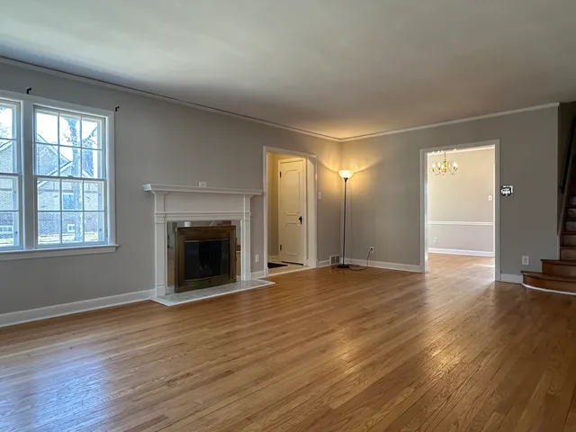 an empty room with wooden floor fireplace and windows