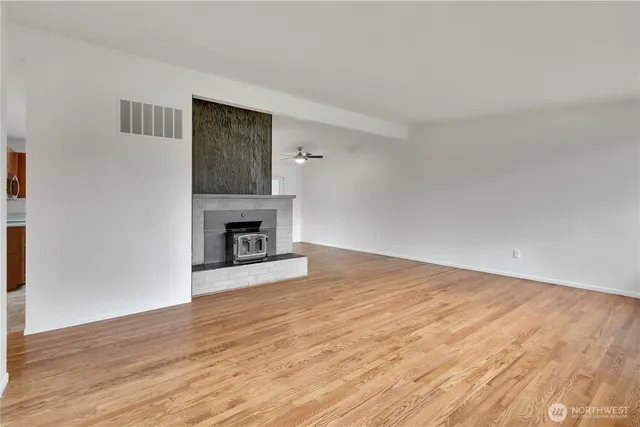 a view of empty room with wooden floor and fireplace