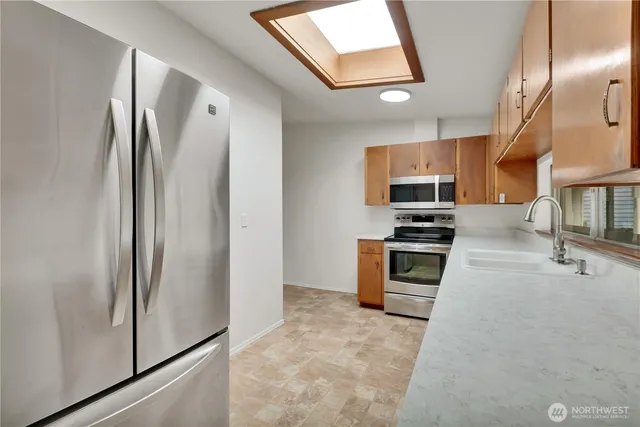 a kitchen with stainless steel appliances granite countertop a refrigerator a stove and a sink with wooden floor