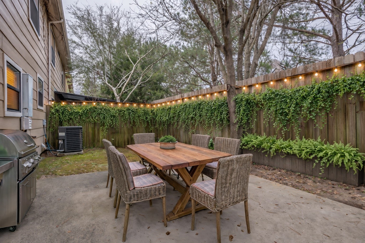 1898 Longmire Road, Unit 5 Conroe, TX 77304 - Photo 2 of 48 Experience enchanting outdoor living with this virtually staged patio, featuring a charming dining setup under twinkling string lights, perfect for cozy gatherings.