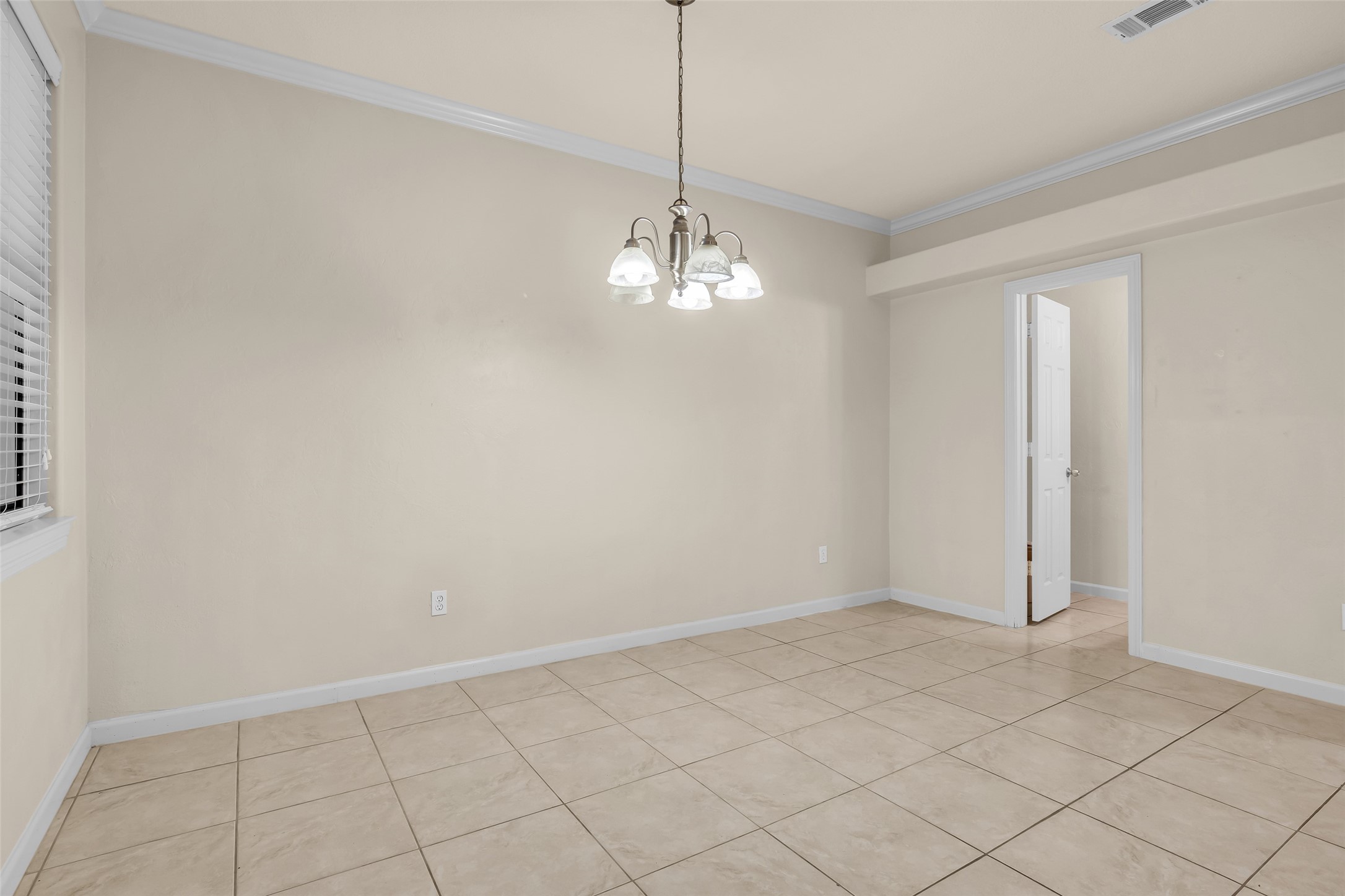 1898 Longmire Road, Unit 5 Conroe, TX 77304 - Photo 27 of 48 This room is spacious with neutral-colored walls and tile flooring. It features a ceiling light fixture and a large window with blinds, providing natural light. A doorway leads to an adjacent area, offering versatile use.