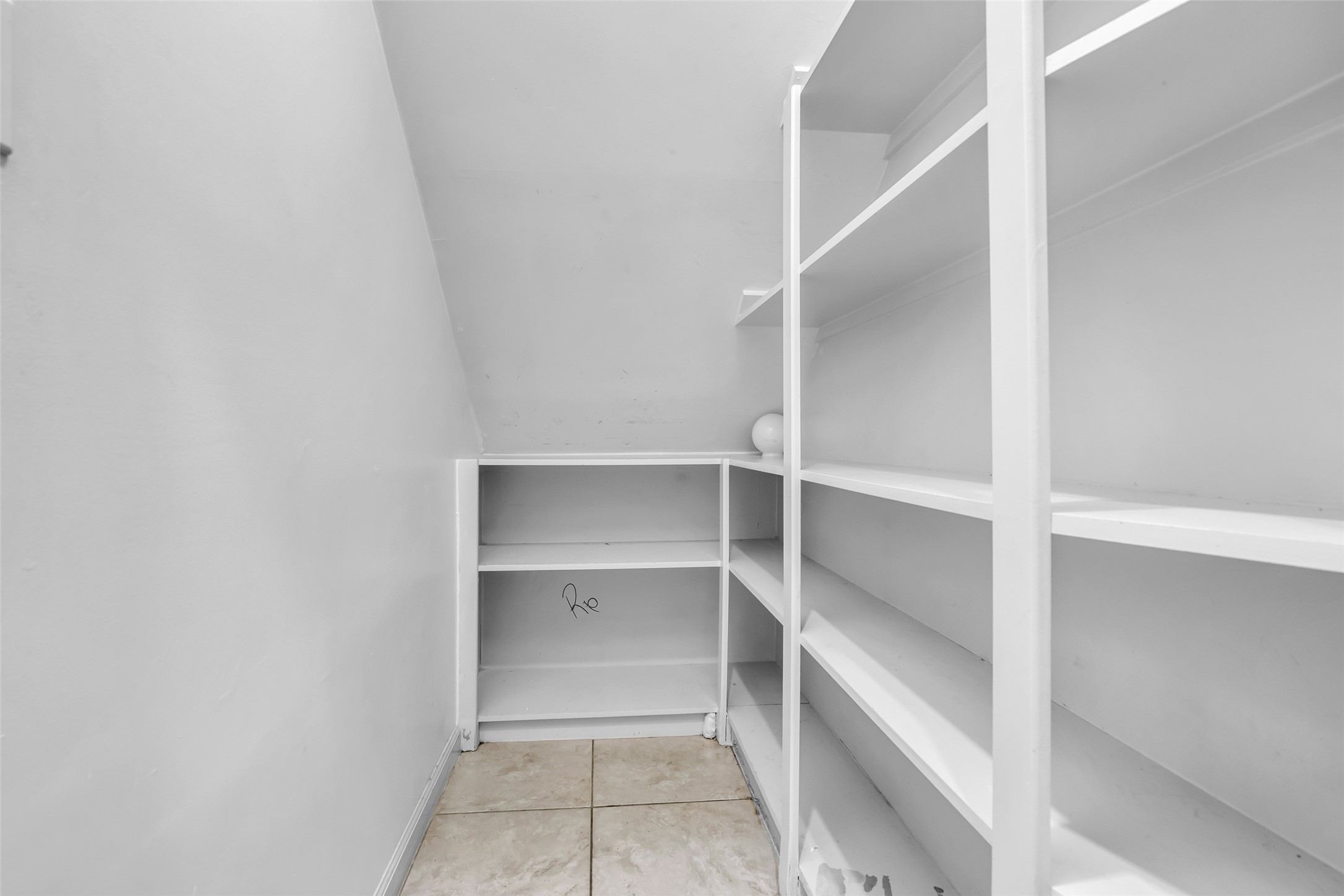 1898 Longmire Road, Unit 5 Conroe, TX 77304 - Photo 30 of 48 This photo shows a small, white storage space with built-in shelving and tiled flooring, ideal for organizing household items.