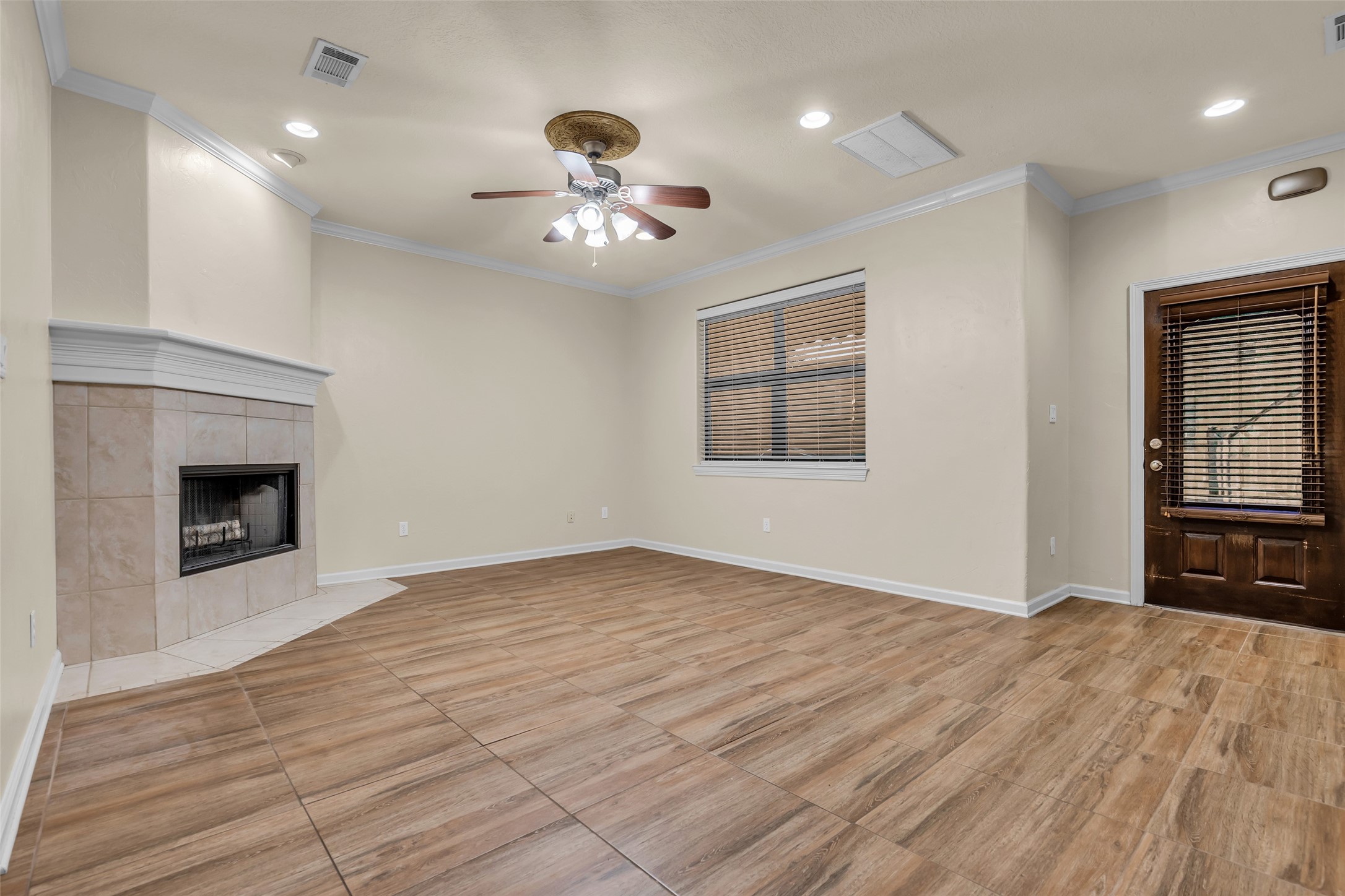 1898 Longmire Road, Unit 5 Conroe, TX 77304 - Photo 9 of 48 This spacious living room features a modern tile floor, a cozy corner fireplace, and ample natural light through a large window. It includes a ceiling fan and a door leading outside, offering both comfort and functionality.