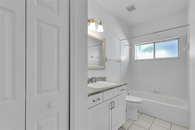 a bathroom with a granite countertop sink a toilet and bathtub