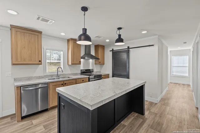 a kitchen with a sink a counter top space stainless steel appliances and wooden floor