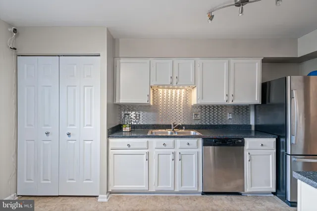 a kitchen with granite countertop white cabinets and stainless steel appliances