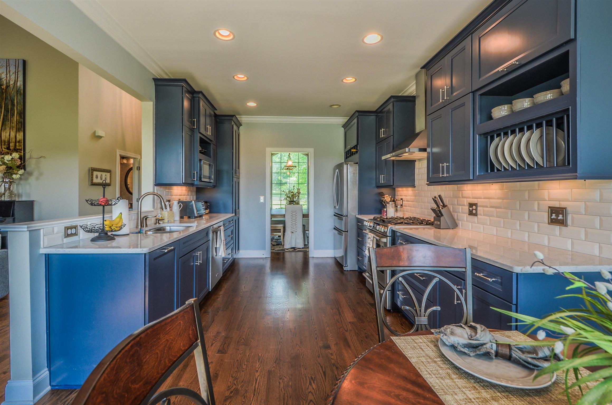 4097 Trinity Road Franklin, TN 37067 - Photo 17 of 30 a kitchen with stainless steel appliances kitchen island granite countertop a table chairs in it and wooden floors