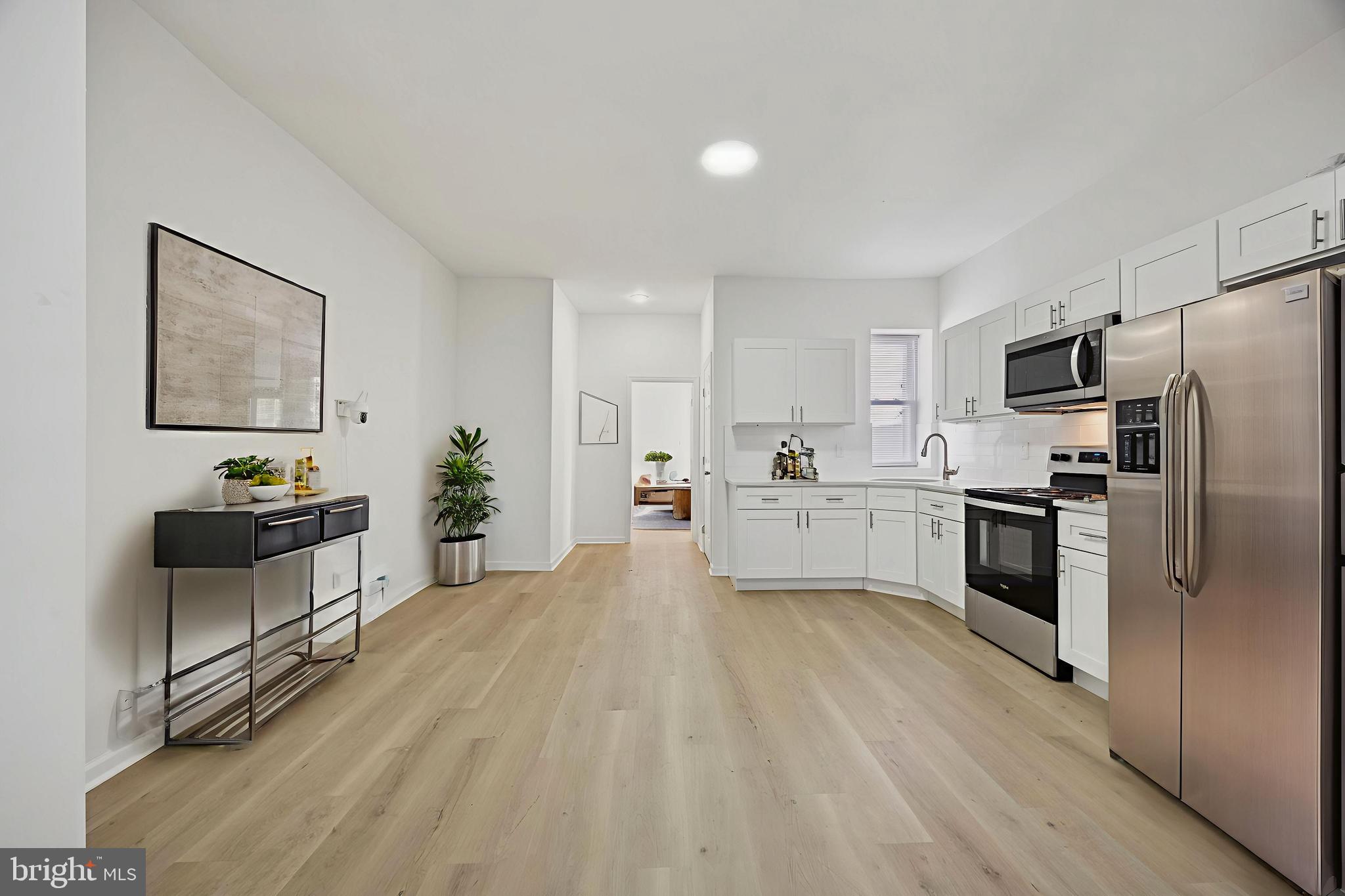 278 South 60th Street Philadelphia, PA 19139 - Photo 4 of 20 a kitchen with white cabinets and stainless steel appliances