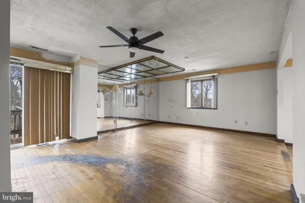 a view of an empty room with window and wooden floor