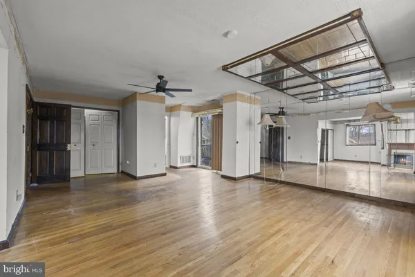 an empty room with wooden floor a ceiling fan and windows