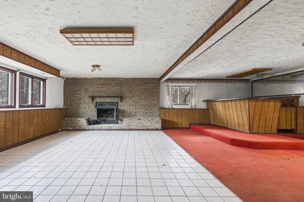a view of an empty room with wooden floor and a fireplace