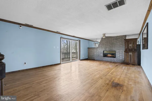 a view of empty room with wooden floor and fireplace