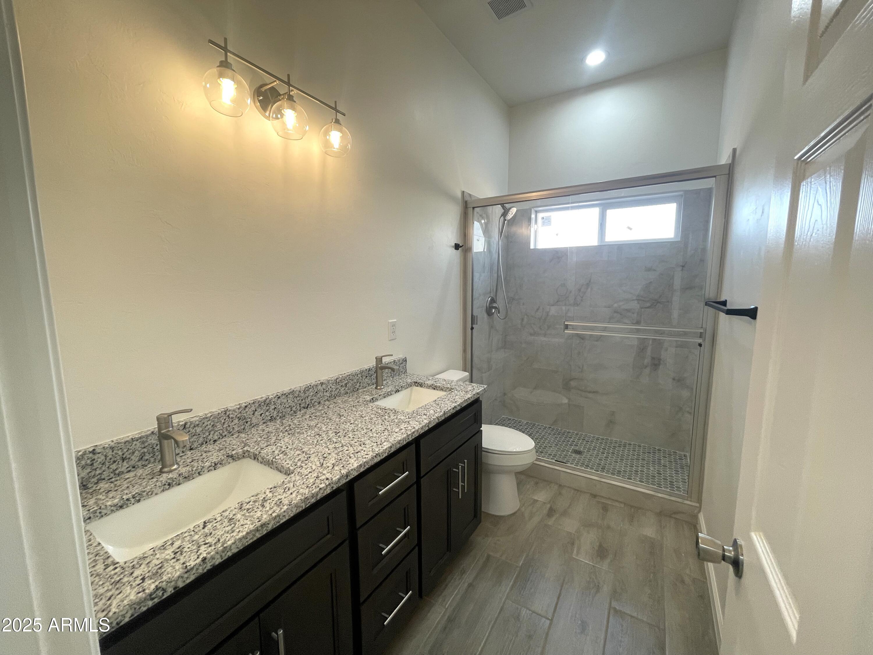 1798 Birmania Corte Rio Rico, AZ 85648 - Photo 17 of 27 a bathroom with a granite countertop sink a toilet and shower