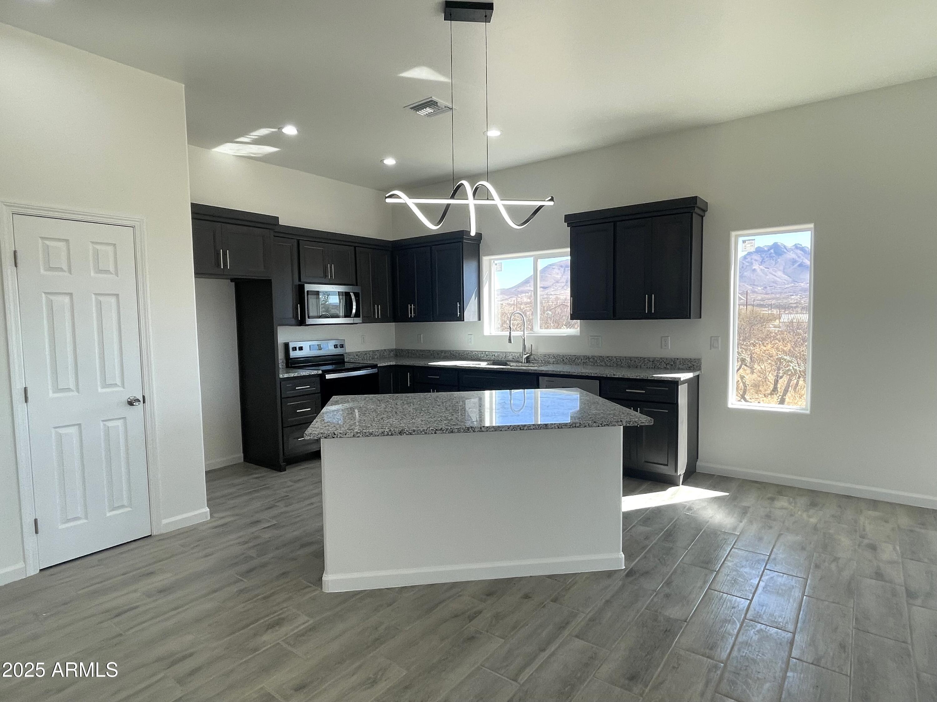 1798 Birmania Corte Rio Rico, AZ 85648 - Photo 6 of 27 a kitchen with stainless steel appliances granite countertop a stove top oven a sink dishwasher a refrigerator and a oven with wooden floor