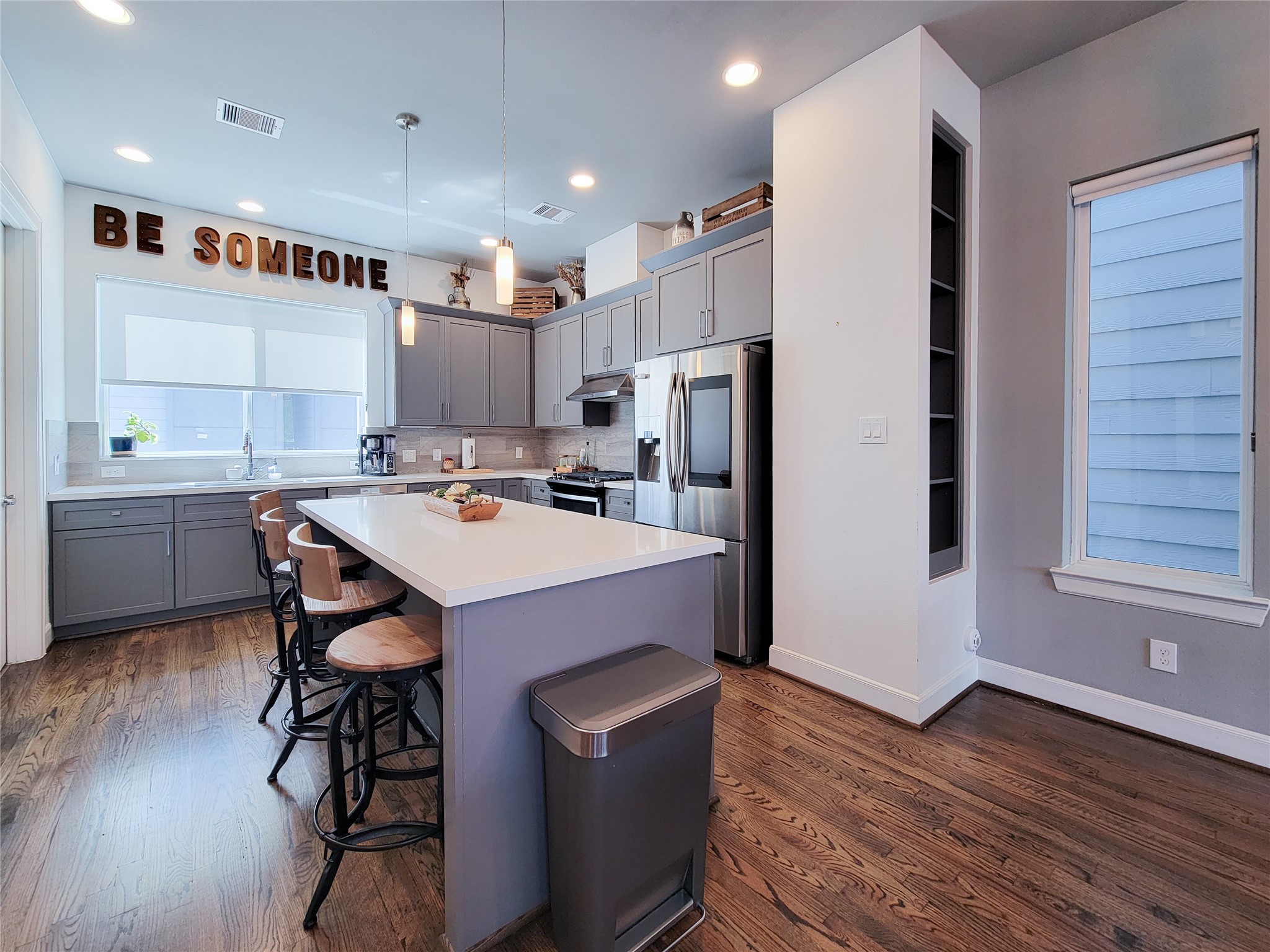 1705 Eado Point Lane Houston, TX 77003 - Photo 25 of 50 This modern kitchen features sleek gray cabinetry, a large island with seating, stainless steel appliancesthat include a beverage fridge, screened refrigerator, microwave, and dishwasher. Hardwood floors. Natural light pours in through the windows, creating a bright and welcoming space.