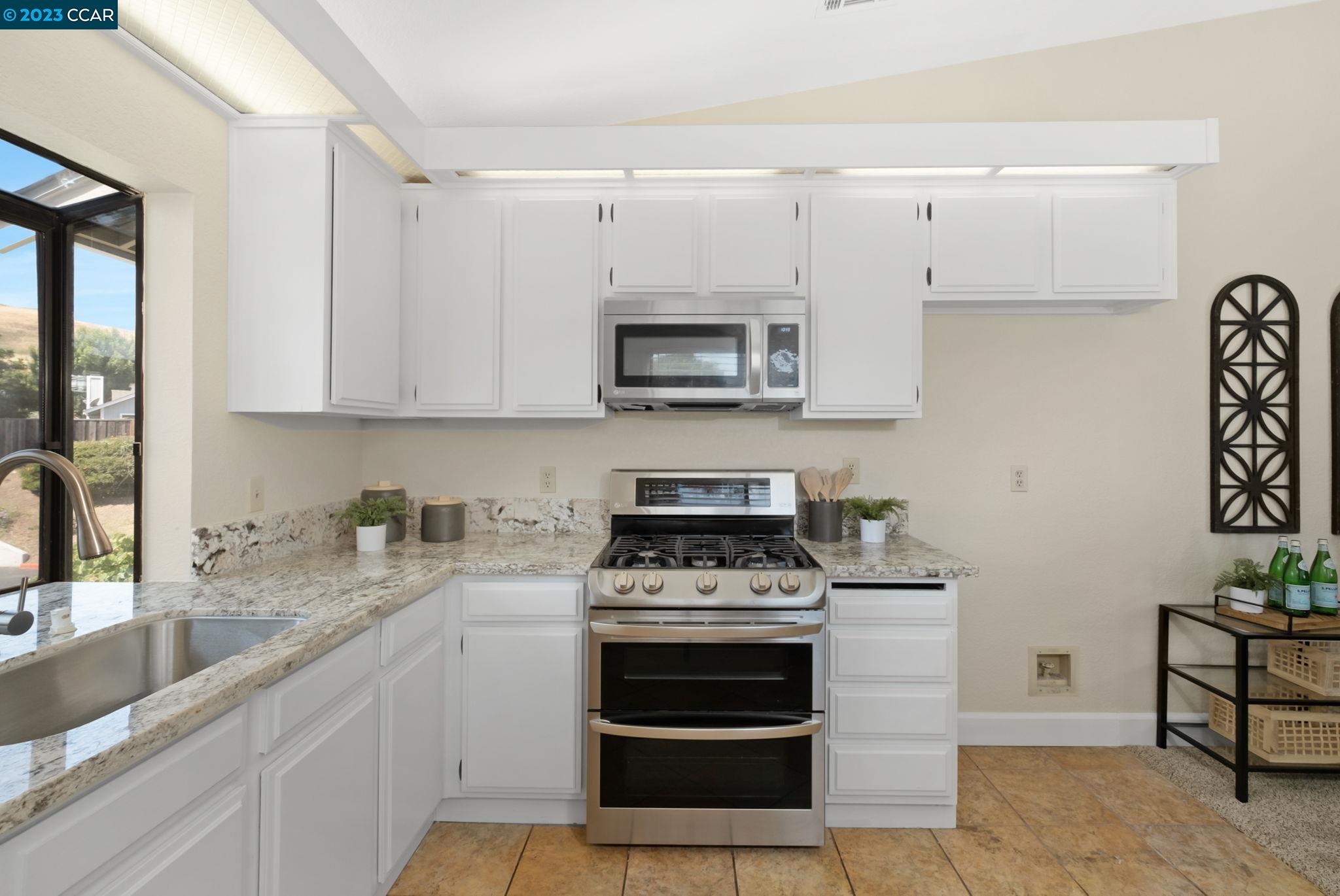 570 Bustos Place Bay Point, CA 94565 - Photo 13 of 26 a kitchen with granite countertop a stove a sink and a microwave