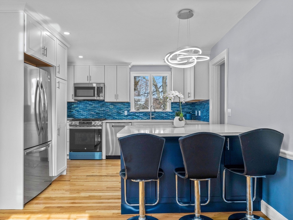 7 Neillian Crescent Boston, MA 02130 - Photo 5 of 29 a kitchen with kitchen island granite countertop a table chairs a sink dishwasher refrigerator and cabinets