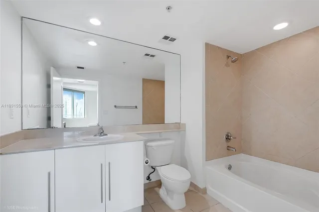a bathroom with a granite countertop sink mirror toilet and bathtub