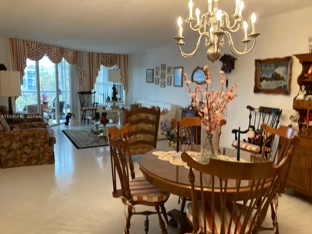 a view of a dining room with furniture a chandelier and large windows