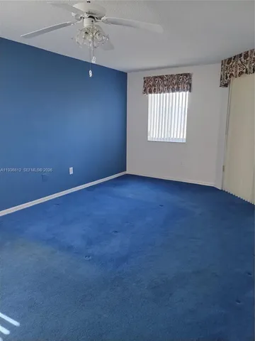an empty room with a window and a ceiling fan