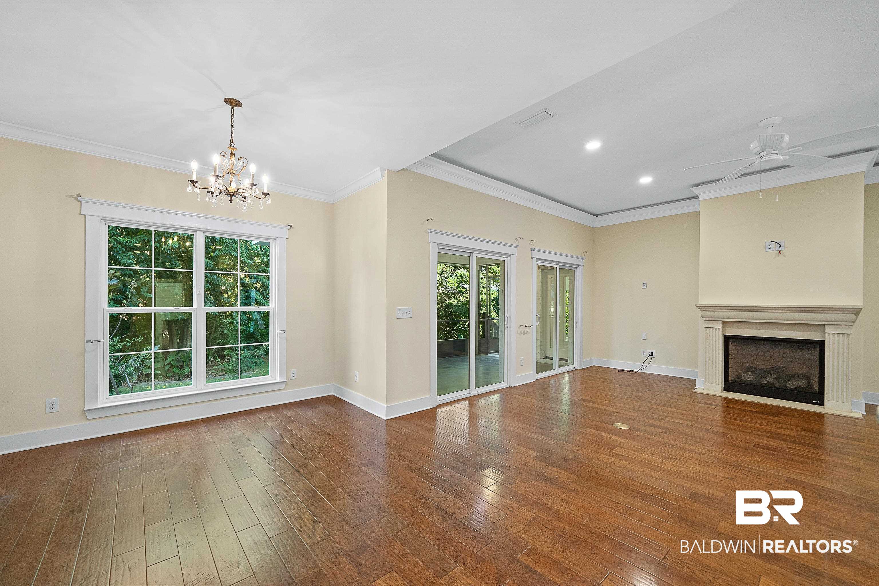 356 Liberty Street Fairhope, AL 36532 - Photo 6 of 39 Unfurnished living room featuring ornamental molding, hardwood / wood-style floors, a fireplace with flush hearth, a chandelier, and recessed lighting