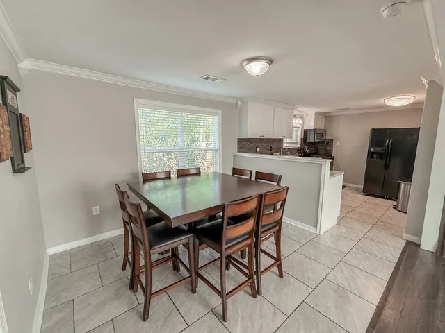 a kitchen with a dining table chairs and refrigerator