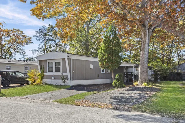a front view of a house with a garden and tree