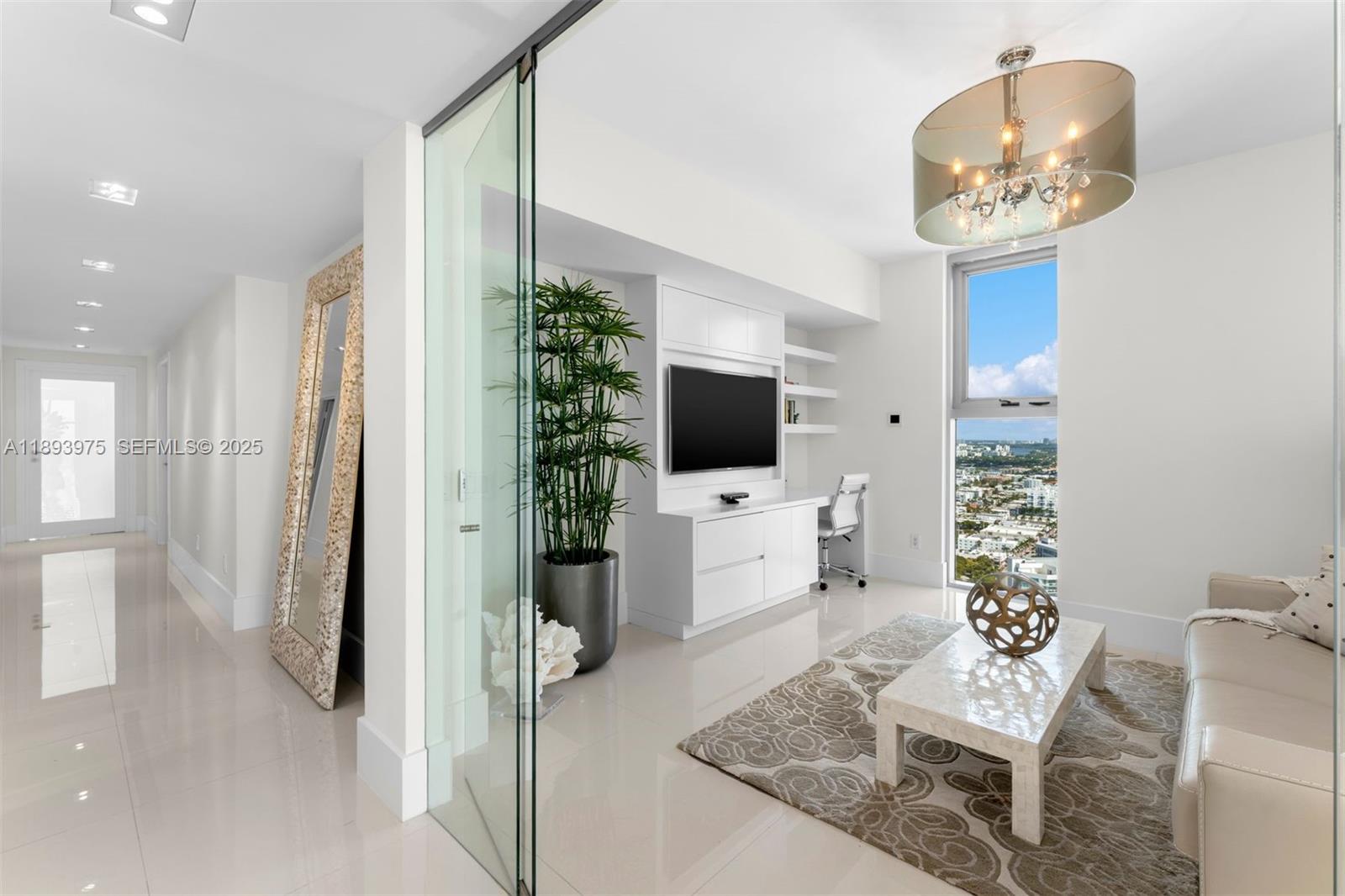 6899 Collins Avenue, Unit LPH04 Miami Beach, FL 33141 - Photo 19 of 29 a living room with furniture a chandelier and a flat screen tv