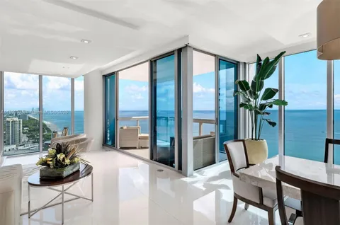 a dining room with furniture and large windows