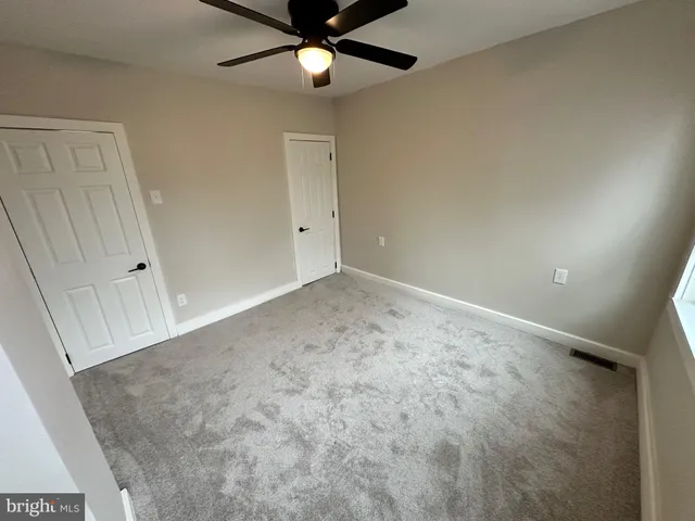 an empty room with a ceiling fan and carpet