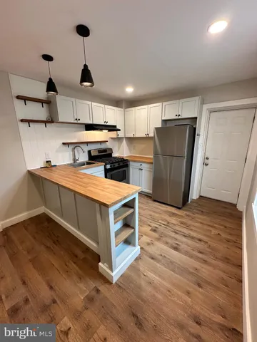 a kitchen with a stove a refrigerator and wooden floor