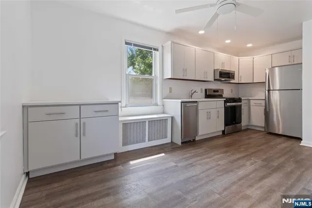 a kitchen with cabinets wooden floor and stainless steel appliances