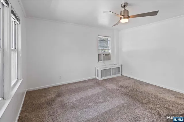 an empty room with windows and ceiling fan